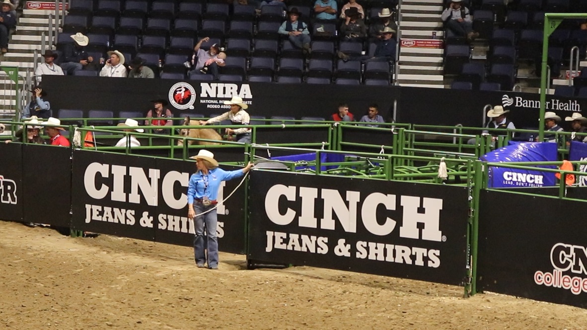 A glimpse of the CNFR 2025 arena featuring the new wrap design, showcasing prominent branding for CINCH Jeans & Shirts amidst the bustling rodeo atmosphere.